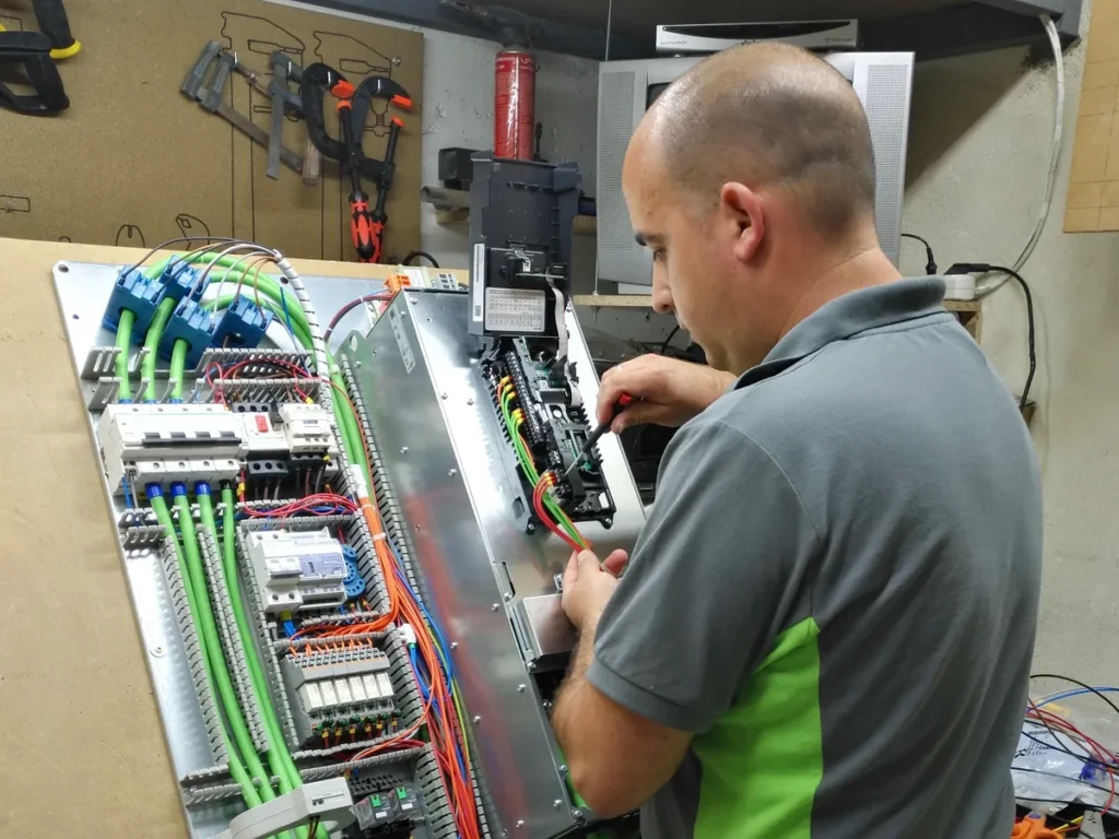 Técnico de ElectroSolution cableando la placa de un cuadro en el banco del taller