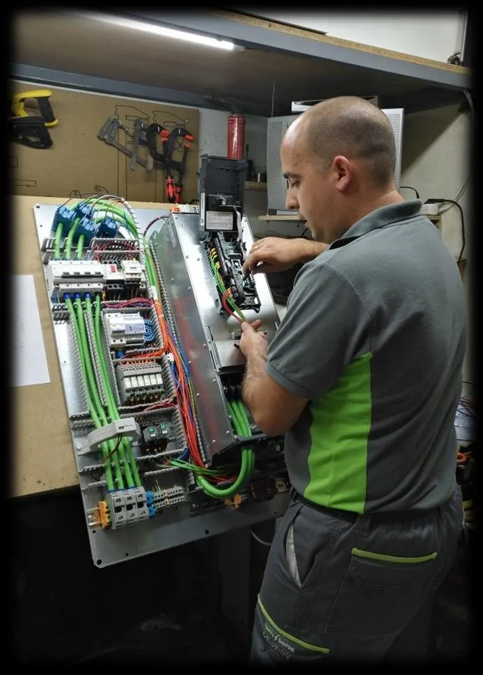 Técnico cableando la placa de un cuadro en el banco del taller